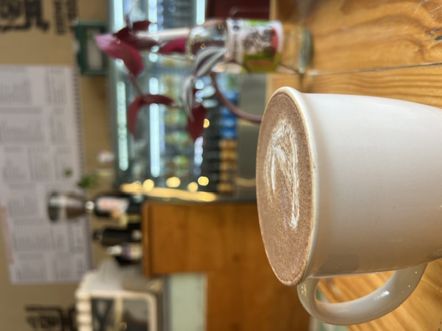 Capuchino servido en taza blanca sobre la barra de madera de Esencia y Raíz Puebla