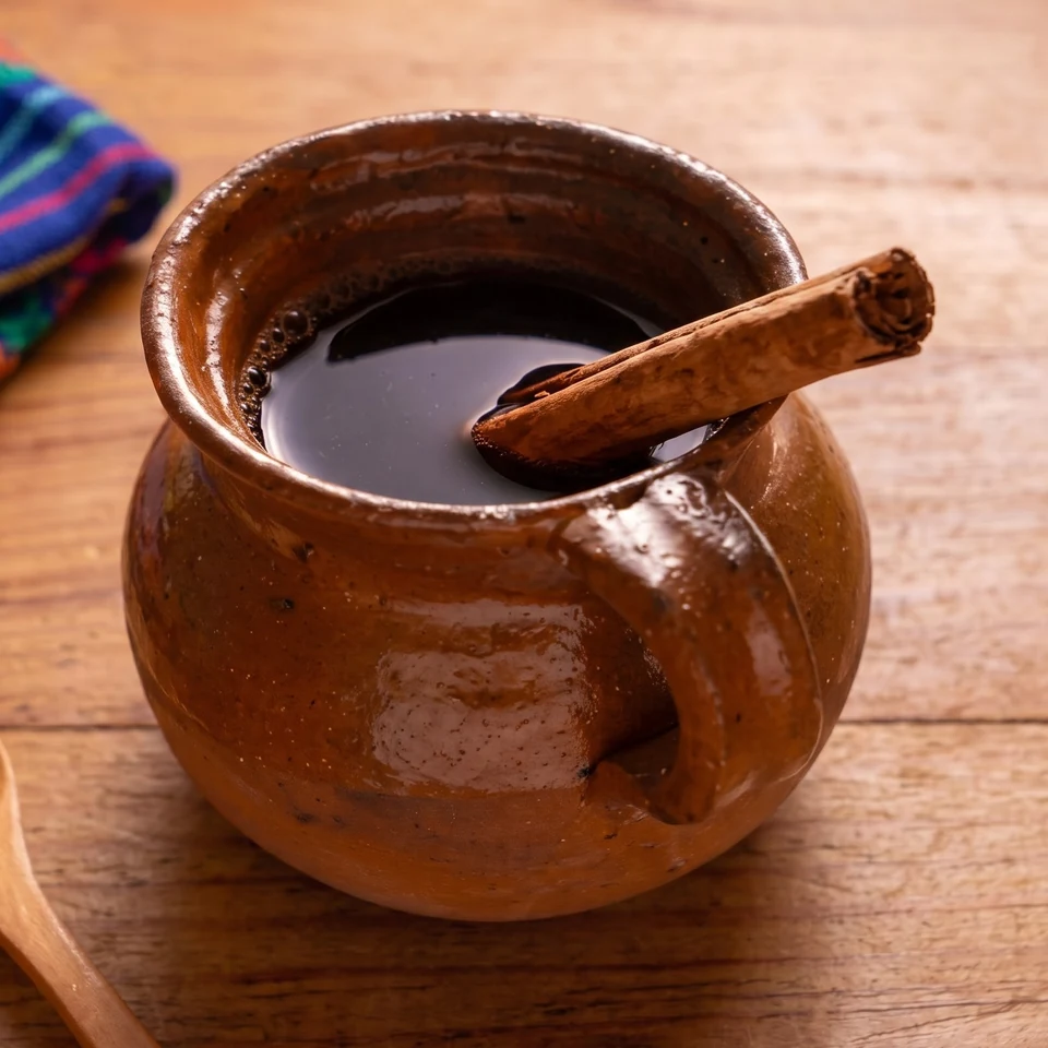 Olla de barro con café de olla y una raja de canela