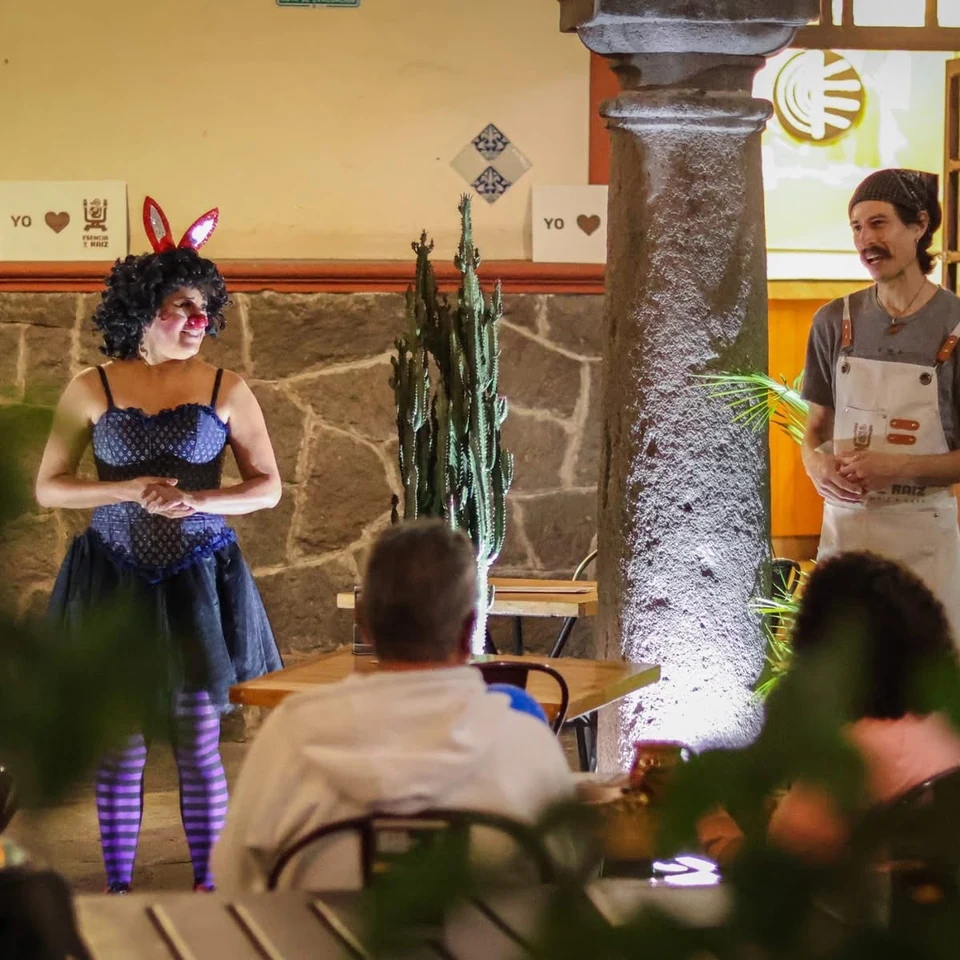 Artista con orejas de conejo y nariz de payaso durante una presentación en el patio de Esencia y Raíz